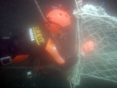 潜水訓練中ネットをくぐる潜水士